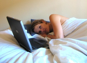 Photo of woman using laptop in bed